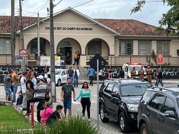 foto de um grupo de pessoas em pé, olhando para a câmera. Elas estão no pátio de uma escola 