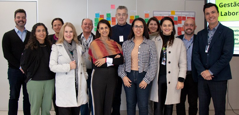 Workshop “Técnicas de Facilitação para Reuniões” é realizado para coordenadores do TRE-PR A fotografia é de um grupo de doze pessoas que estão sorrindo para a câmera. Eles estão em uma s...