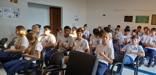 Fotografia que retrata um grupo de jovens posando para uma foto em frente à fachada do Fórum Ele...