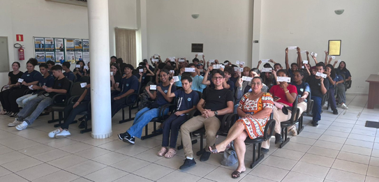 Fotografia que retrata um grupo de jovens posando para uma foto em frente à fachada do Fórum Ele...