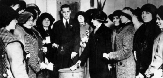 Foto em preto e branco, com um grupo de mulheres votando.