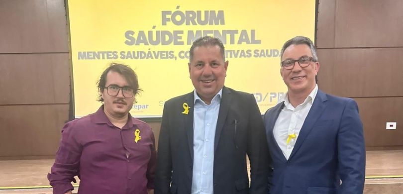 Assessoria de Atenção à Saúde do TRE-PR participa de fórum de saúde mental em Curitiba Fotografia de três homens sorrindo. Os três homens usam fitas amarelas em referência à campanha ...