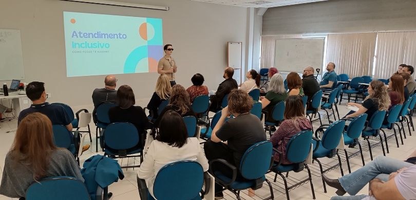 Fotografia do servidor Diogo Fraga falando diante de homens e mulheres, que aparecem sentados em...