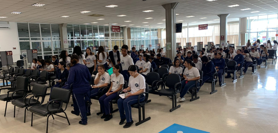 Fotografia que retrata um grupo de jovens posando para uma foto em frente à fachada do Fórum Ele...
