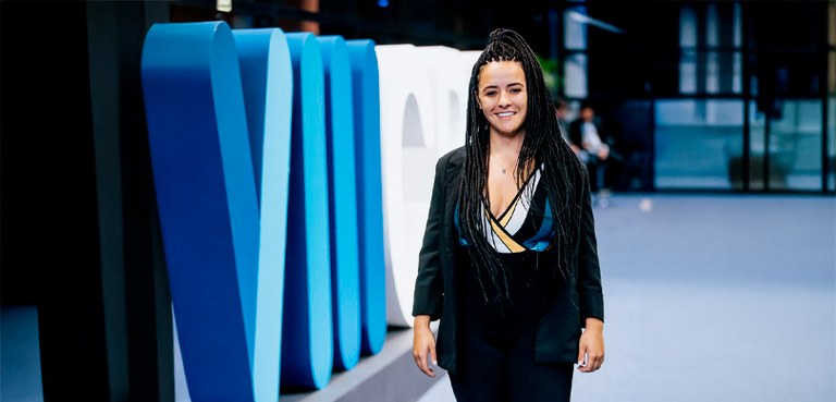 Dia do Advogado: conheça histórias de profissionais da área eleitoral Fotografia da doutora Nahomi Helena posando sorrindo ao lado de um letreiro, nas cores azul e br...