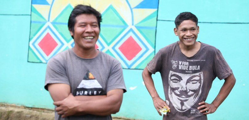 Dois indígenas de uma comunidade em Guaraqueçaba rindo, olhando para o lado direito do quadro. A...