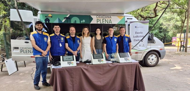 Fotografia na qual se vê um grupo de sete pessoas, composto por cinco homens e duas mulheres, po...