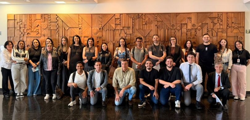Fotografia em plano inteiro de um grupo de cerca de vinte pessoas posando em duas fileiras sobre...