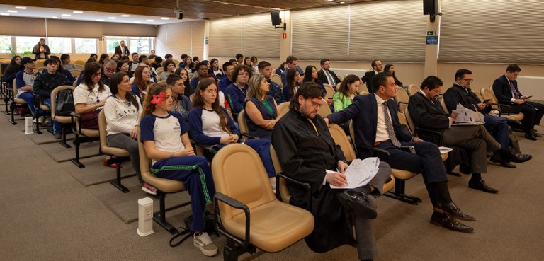 Fotografia na qual é possível ver estudantes sentados na platéia da sala de sessões assistindo à...