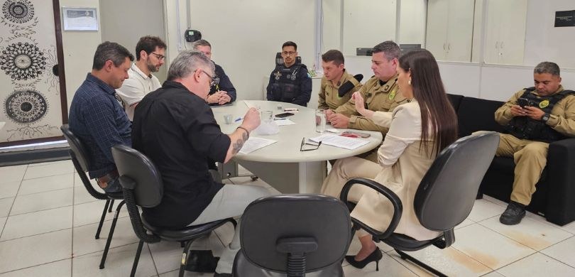 Fórum Eleitoral de Pinhais realiza reunião com órgãos de segurança Em uma sala com paredes brancas, sete homens e uma mulher sentam-se em cadeiras pretas ao redor ...