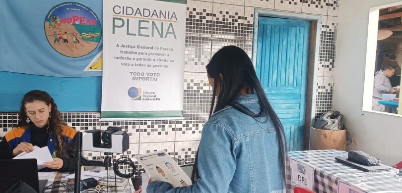 Foto registrada durante atendimento a eleitores em Tibicanga. No centro da imagem, está uma mulh...
