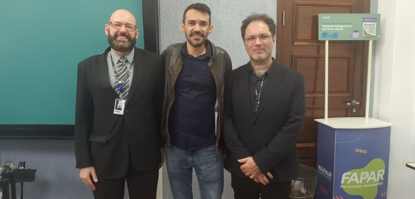 Fotografia em que são vistos posando em uma sala de aula os servidores Roney e Rafael e o profes...