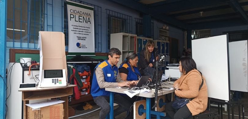 Mutirão do Projeto Aproxima atende eleitorado da comunidade Vila Zumbi dos Palmares, em Colombo, nesta quarta-feira (23) foto captada durante o mutirão. Em um ambiente escolar, um homem e duas mulheres identificados c...
