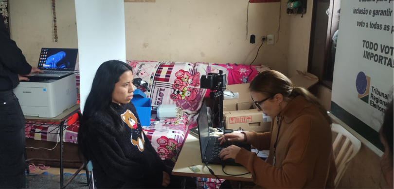 Na foto, duas mulheres estão sentadas uma de frente para a outra. A da esquerda é uma mulher de ...