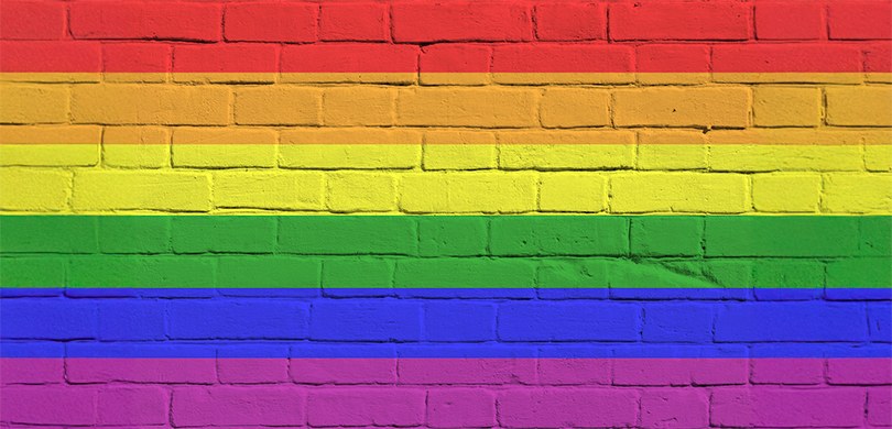 Imagem que remete a uma parede de tijolos aparentes pintada em faixas horizontais nas cores do a...