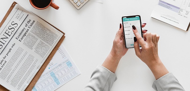 Prazo para apresentação das contas anuais dos partidos termina em 30 de junho Fotografia das mãos de uma mulher mexendo em um smartphone. Ao redor, em uma mesa branca, há um ...