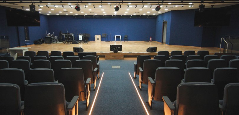 Reinauguração do Auditório do TRE-PR acontece nesta quinta-feira (29) Fotografia de um auditório vazio visto da plateia em direção ao palco. Em primeiro plano, observ...