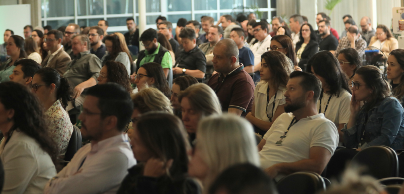 Segundo dia do Kick-Off conta com palestras de tecnologia da informação, planejamento de eleições e cidadania Fotografia de uma platéia, formada por homens e mulheres. Ao fundo, observam-se janelas e uma pa...