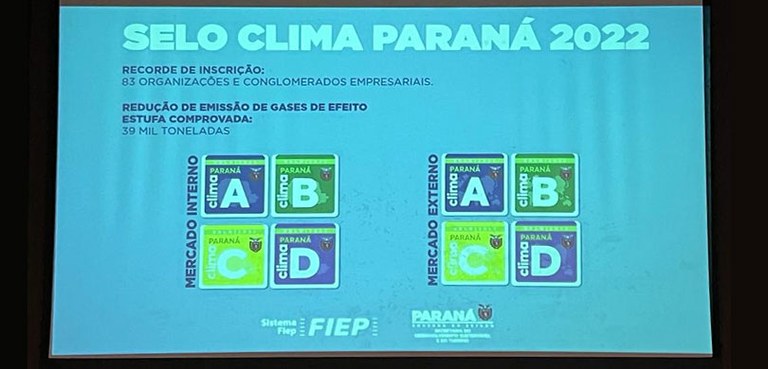 Fotografia de um slide apresentando o Selo Clima Paraná, com o número de inscrições, a redução d...