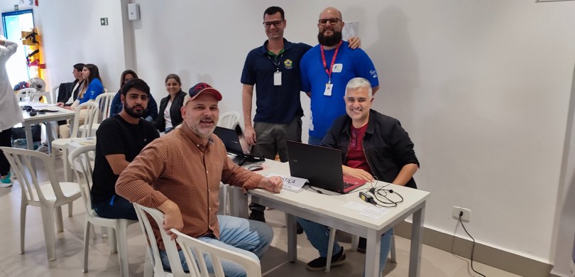 TRE-PR participa do evento SESC Cidadão em Bela Vista do Paraíso Cinco homens posam para a foto ao redor de uma mesa. No fundo da foto, no canto esquerdo, aparec...