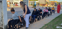 Na imagem, há uma fila horizontal de homens e mulheres em cadeiras de rodas na cor preta. Eles e...