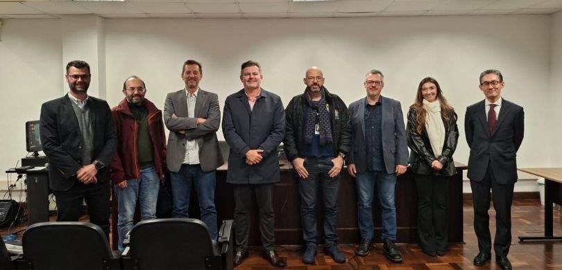 Na fotografia há sete homens e uma mulher posando sorrindo, uns ao lado dos outros. Todos vestem...