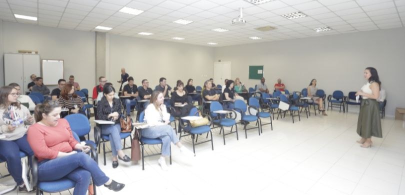 Fotografia na qual é possível ver servidoras e servidores sentados e distribuídos em fileiras de...